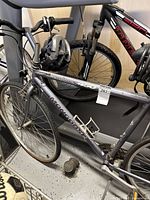 Photo showing side view of the gray Mongoose Crossway 450 frame, front wheel, and part of the handlebars with a helmet hanging from it.