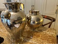 Two hammered silver pots side by side on countertop