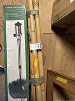 Photo showing boxed garden torch light and bundle of bamboo poles taped together.