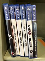 Six PS4 game cases all standing upright showing spines with titles.