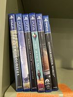 Photo of six PS4 game cases standing side by side showing game titles.