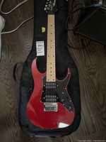 Full view of the red Ibanez electric guitar on top of the black nylon carrying case showing the body, neck, and headstock.