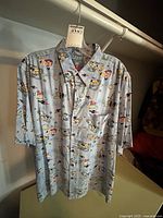 Front view of light blue short sleeve Buzz Lightyear-themed shirt hanging on a hanger showing button up style and short sleeves.