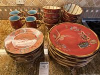 Full set showing stacked plates, bowls, and mugs with detailed floral and gold trimmed design.