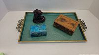 Top view of green brass tray with small wood painted box, blue silk box, and red cinnabar dragon figurine placed on it.