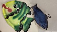 Two fish decor plates displayed together, one large colorful fish plate and one smaller blue fish plate, showing overall size and design.