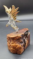 Side angle view of eagle figurine showing gold rimmed wings and clear body supported on wood base.