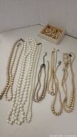 All necklaces laid out showing variety in color and size, loose beads in a box.
