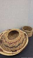 Two large seagrass bowls stacked with a smaller wrapped bowl and a basket beside them, showing the variety and size differences.