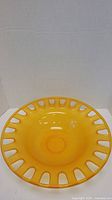 Top view of large yellow bowl showing cutout rim pattern and glossy surface.