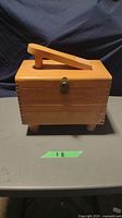 Closed view of the wooden shoe shine box with handle and brass latch.