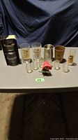 Overall view of liquor branded glassware, miniature shot glasses, and unique bottle opener on a table