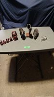 Photo of assorted figurines including Buddha statues and various carved animals on a folding table with dark backdrop.