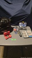 Full view of all items including tool bag, torque ratcheting screwdriver, drill driver set and two bit sets on a gray table.