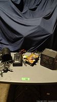 Four black electronic items including two power inverters, a fan, and a portable heater laid out on a table.