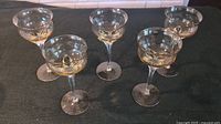 Set of five amber crystal wine glasses arranged on a black surface, showing their shape and amber coloration.