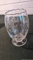 Full view of clear glass vase showing swallowtail and floral etched designs, scalloped rim and footed base.