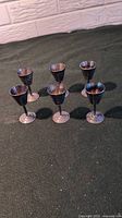 Set of six silver goblets arranged on a flat surface showing the overall shape, size, and design.