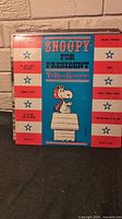 Front cover of 'Snoopy for President' vinyl album by The Royal Guardsmen featuring cartoon of Snoopy on a blue and red striped background.