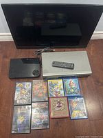 RCA 32-inch TV without stand, DVD player, Blu-ray player, remote, and 8 CDs arranged on floor