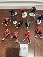 Overview of the 12 ice hockey action figures on a wooden floor, showing various poses and colors.