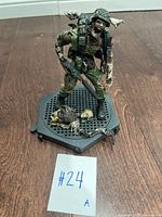 Front angle showing detailed zombie soldier figure with rifle, military gear, and severed zombie parts on hexagonal base.