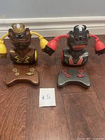 Two SilverLit YCOO Robo Kombat Viking remote control robots side by side with their controllers on the floor.