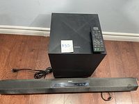 Sony HT-CT260 soundbar with power cable, wireless subwoofer and remote control placed on wooden floor