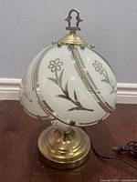 Side view of vintage dome lamp showing gold metal base and frosted glass shades with floral motifs
