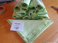 Stack of rolled pale green napkins with folded example