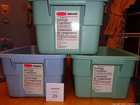 Three labeled Rubbermaid totes stacked—two green, one blue