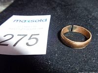 Broken 10K stamped gold ring on dark surface showing split and overall appearance