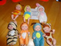 Group shot of eight small clothed dolls on table