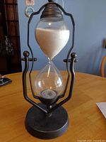 Full view of hourglass showing metal frame, glass bulbs, sand, and base