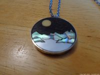 Front view of pendant showing intarsia landscape and silver bezel