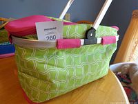 Green patterned insulated picnic basket with folded aluminum handle and pink trim