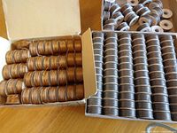 Open boxes showing rows of copper and brown thread bobbins plus additional circular bobbins