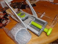 Mandoline slicer with pusher and clear catch tray, parts visible