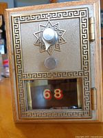 Front view showing brass lockbox door, Greek-key border, star dial, number 68 window