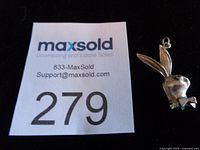 Front view of sterling silver Playboy bunny charm beside lot number card