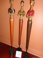 Full view of three wooden statues on bases with lot card