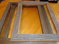 Three barnwood frames laid out on table showing front and attached hanging wires