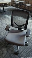 Front angle photo showing padded seat, mesh backrest, and armrests on the chair
