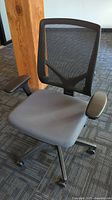Front view of adjustable office chair with mesh back and padded seat, on caster wheels, with black armrests.