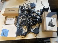 Mixed lot of headsets and boxes on white table, tangled wires visible