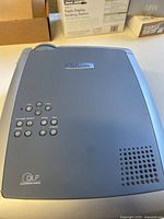 Top view of light grey InFocus X1 projector showing control buttons, logo and ventilation holes.