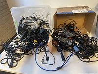 Wide view of two containers filled with various tangled computer cables and power cords.