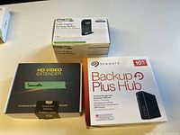 Three sealed product boxes: Plugable docking station, HD video extender, Seagate Backup Plus Hub