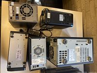 Overhead view of five NAS units with power adapters and cables on table