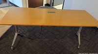 Top view of a rectangular office desk with a wood finish, showing built-in central power outlets.